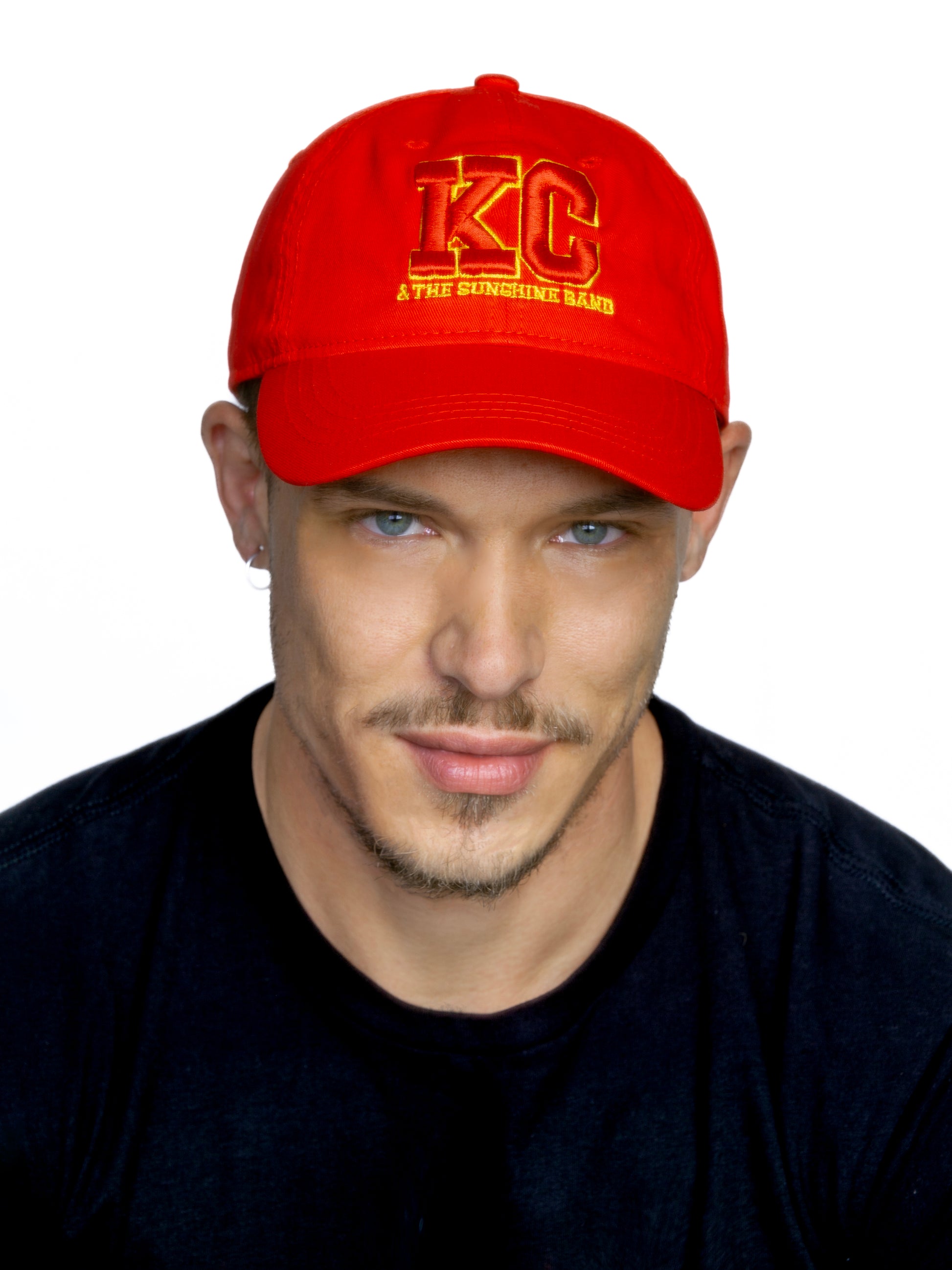 Man wearing a red cap with 'KC' and 'The Sunshine Band' text on a white background