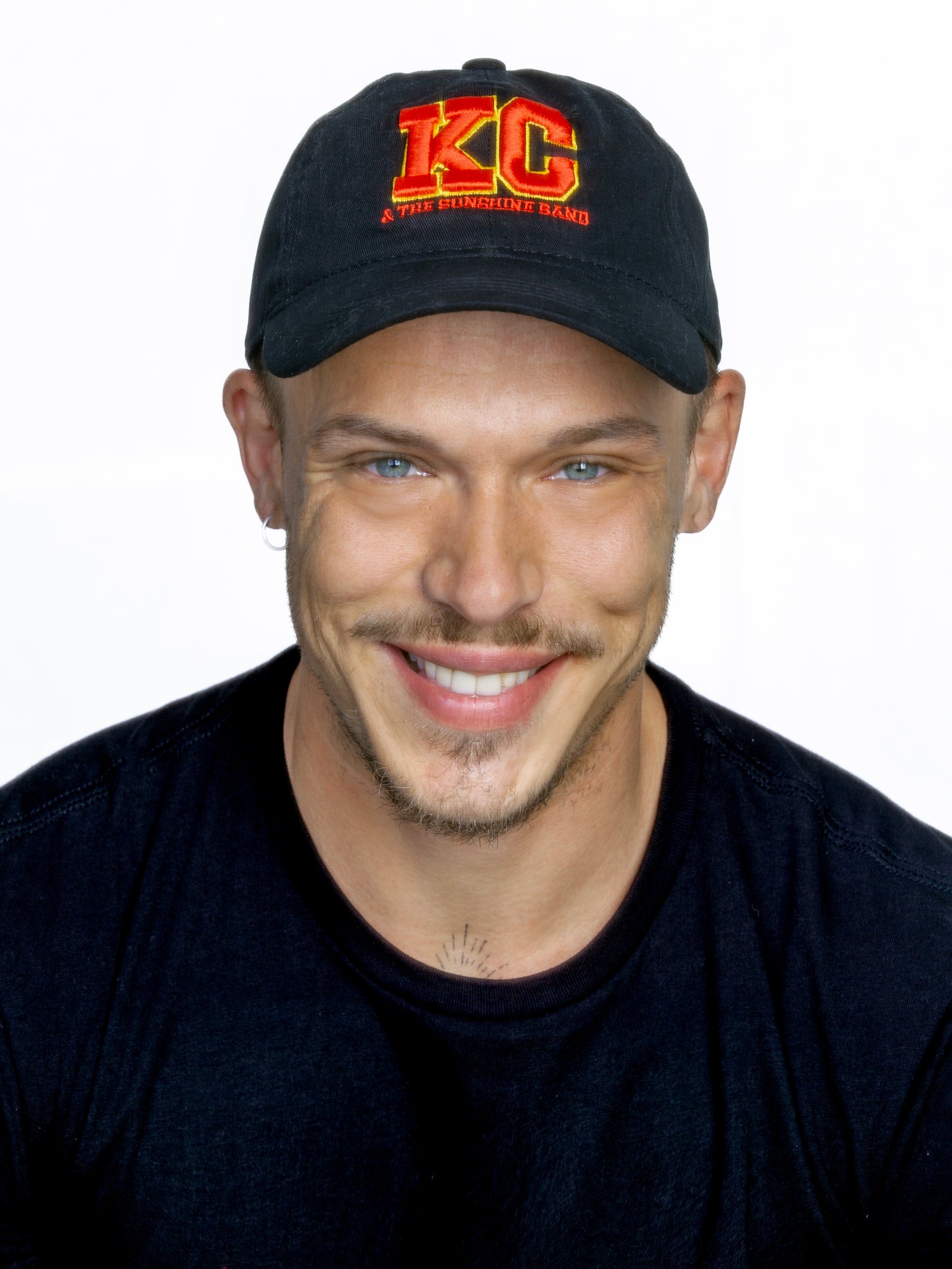 A person wearing a black 'KC' logo cap with a red embroidered 3D design.