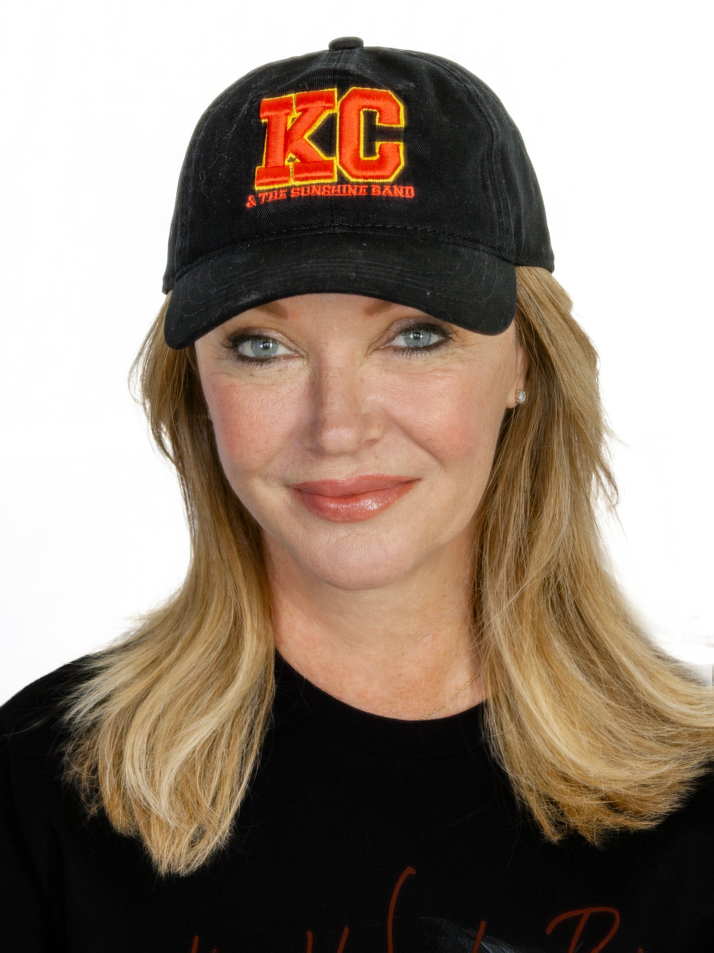 A person wearing a black 'KC' logo cap with a red embroidered 3D design.